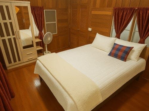 The en-suite guest bedroom at Suan Na Ta Bua organic farmstay, with a neatly made bed and simple, comfortable furnishings.