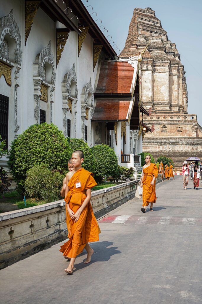 พระสงฆ์สองรูปในจีวรสีส้มเดินผ่านลานวัดไทย