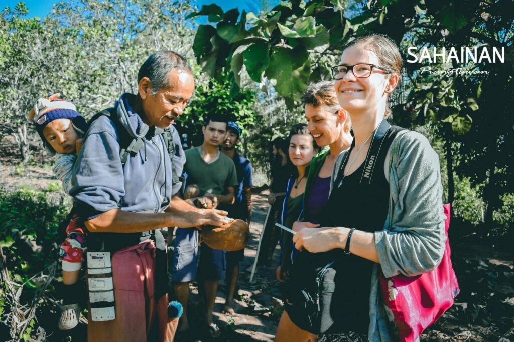 Teacher demonstrating wild food preparation to students on a foraging walk at Sahainan