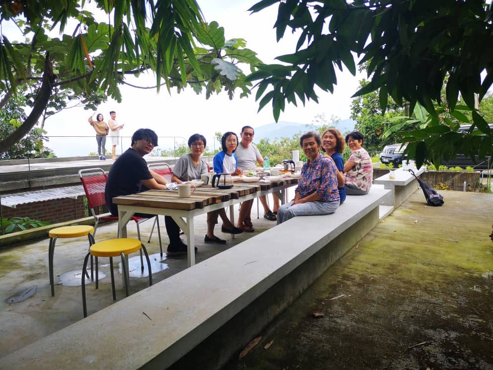 A group seated at a long table on the Bamboo Retreat terrace, with hills in the distance